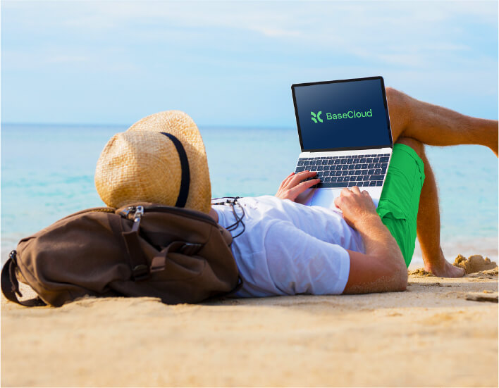 Person comfortably lying on a beach, typing on a laptop